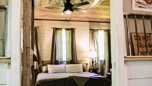 Quarto rústico com cama, ventoinha no teto e placa de 'Não Perturbe'.