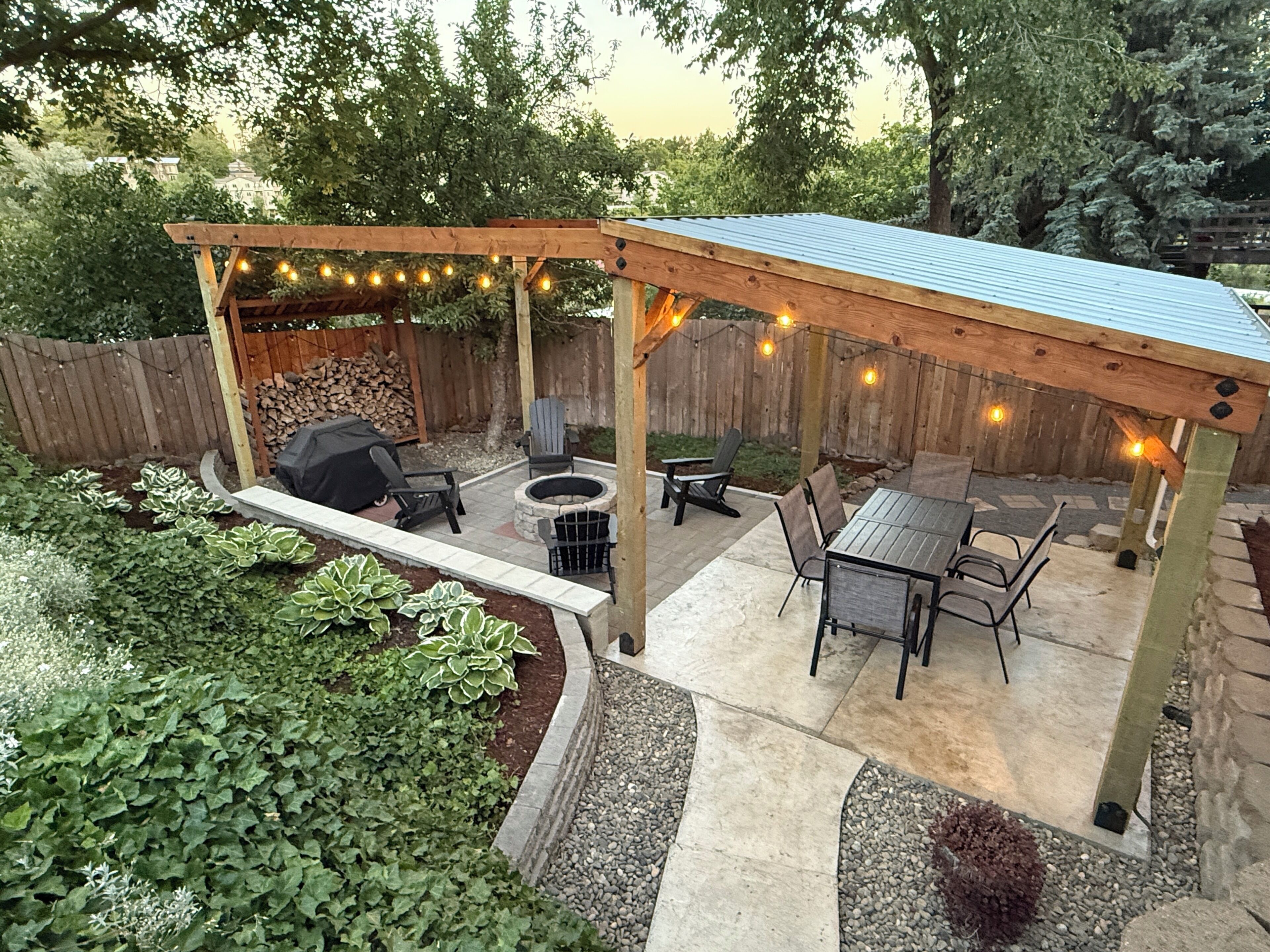 A covered patio area with seating, a fire pit, and string lights.
