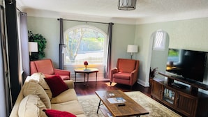 A living room with a sofa, two armchairs, a coffee table, a TV, and a view of the outdoors. - State Street Cottage, 2BR Apt (Pullman)