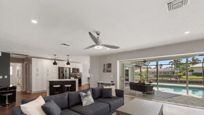 Ein modernes Wohnzimmer mit grauem Sofa, einem Couchtisch und Blick auf Pool und Außenbereich.