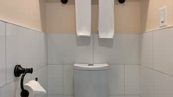 A bathroom with a toilet, a towel rack with two towels, and a toilet paper holder.