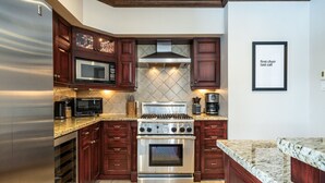 A kitchen with dark wood cabinets, stainless steel appliances, granite countertops, and a tiled backsplash.
