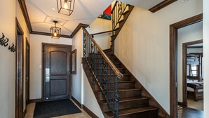 A wooden staircase with a dark handrail and a light fixture above it.