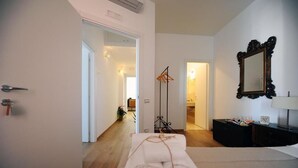 A hotel room with a wooden floor, a white door, a mirror, a black dresser, and a towel on the floor. - Vista Sui Sassi (Matera)
