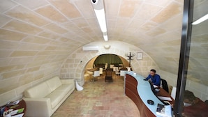 An arched reception area with a receptionist desk, a sofa, and a dining area with tables and chairs. - Vista Sui Sassi (Matera)