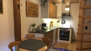 Une cuisine compacte avec des meubles en bois, un four encastré et un coin repas comprenant une table et des chaises.