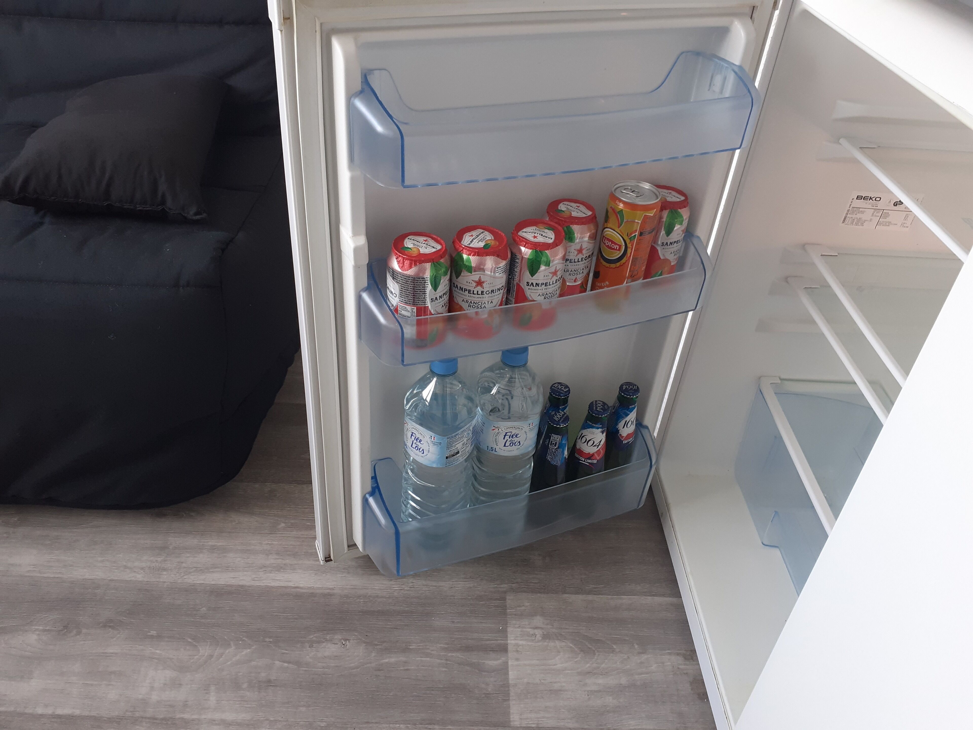 Ett kylskåp med hyllor fyllda med drycker och vattenflaskor.