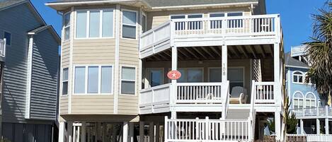 A two-story building with a balcony on the second floor, a visible number '108', and a clear blue sky in the background.