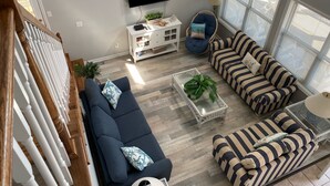 En moderne stue med stort fjernsyn, to sofaer, et sofabord med planter og et hvidt skab.