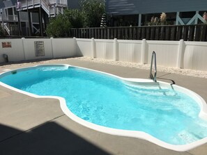 Una piscina con plataforma blanca, escalera de metal y un letrero que dice 'No Diving'.