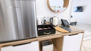 Una cocina moderna con un refrigerador Hisense de acero inoxidable, una cafetera, un hervidor de agua, un teléfono y una tabla de cortar de madera.