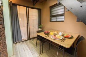 Un área de comedor con una mesa lista para el desayuno, incluyendo platos de comida, un tazón de fresas y un vaso de jugo de naranja.