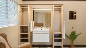 Un baño moderno con tocador, espejo y estantes para guardar objetos.