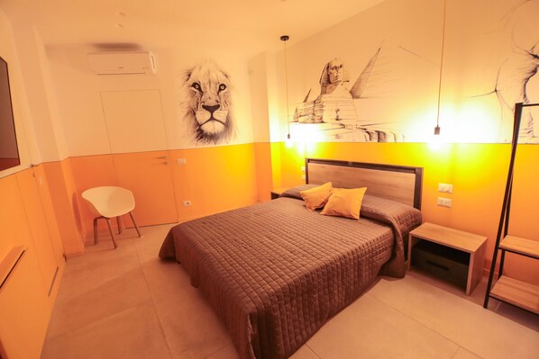 A bedroom with a large bed, a chair, a nightstand, and a wall mural.