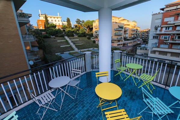 Un balcón con piscina, mobiliario exterior y vistas de edificios circundantes.