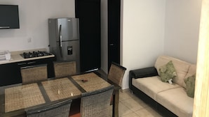 A compact kitchen with a refrigerator, stove, and dining area with chairs and a table.