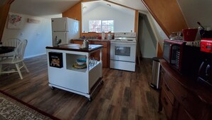 Una cocina compacta con una isla central, un refrigerador, un horno y un microondas.