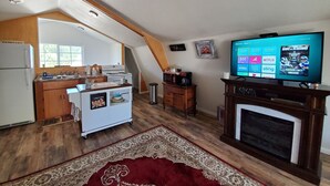 Un loft espacioso con cocina, comedor y un televisor de pantalla plana grande.