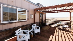 Un patio in legno con sedute all'aperto, una pergola e vista su un paesaggio desertico.