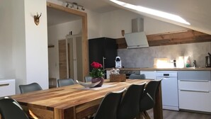 Une cuisine moderne avec une table à manger en bois, des chaises noires et un lave-vaisselle blanc.
