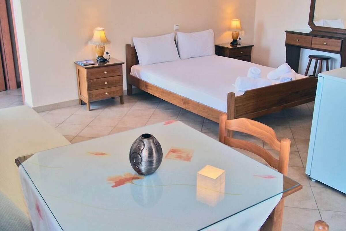 A hotel room with a bed, bedside tables, a desk, and a chair.