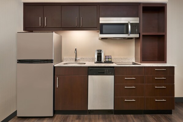 A modern kitchen with a refrigerator, dishwasher, microwave, and a coffee maker on the countertop.