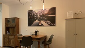 Ein Essbereich mit einem Holztisch, zwei Stühlen, einem Schrank und einem Gemälde einer Berglandschaft.