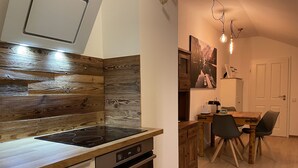 Eine moderne Küche mit Holzrückwand, eingebautem Ofen und einem Essbereich mit Tisch und Stühlen.