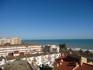 Un hotel costero con varios pisos, balcones y vista al mar.