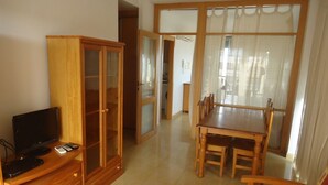 A living room with a TV, wooden cabinet, dining table, and chairs. - P. Maritimo 40 Lateral LEK (Peñiscola)