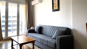A living room with a grey sofa, a wooden coffee table, a wall-mounted air conditioner, and a framed picture on the wall. - P. Maritimo 40 Lateral LEK (Peñiscola)