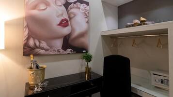 A modern room with a black desk, a large painting, a plant, and a microwave on the counter.