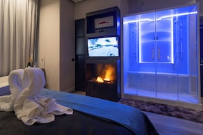 Habitación de hotel con chimenea, televisor y armario con puertas iluminadas.