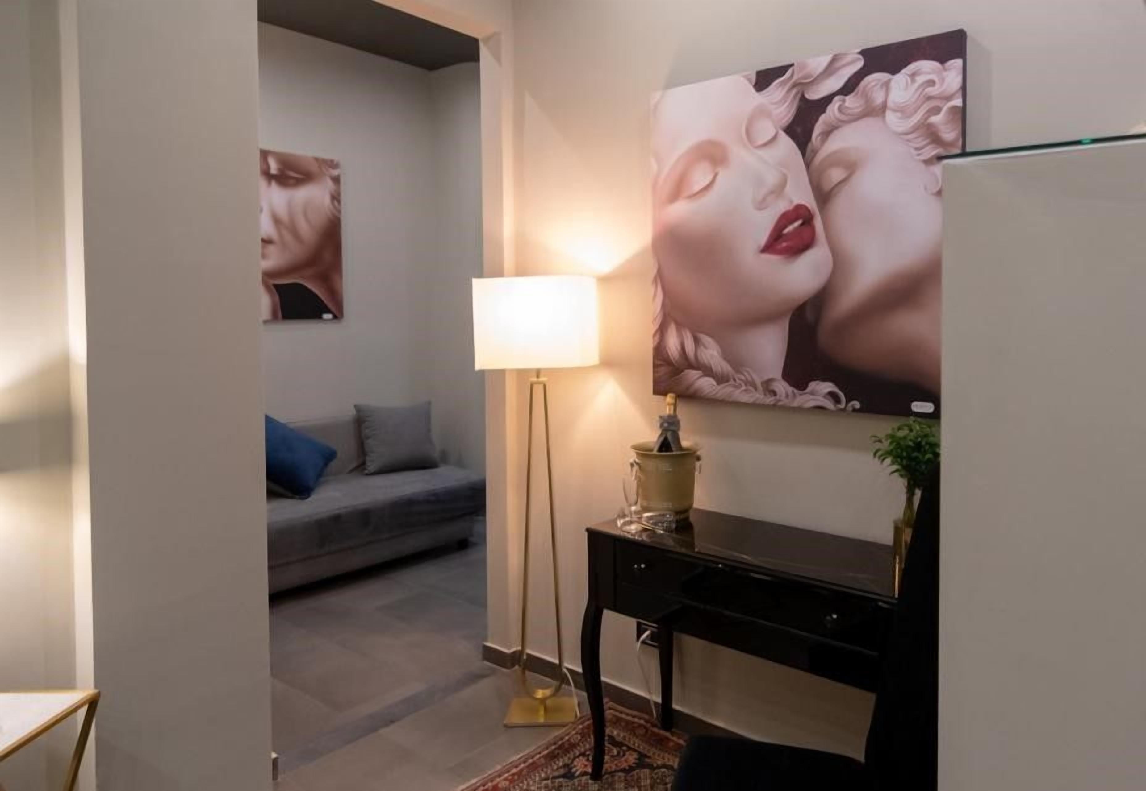 Une pièce comprenant un canapé, une lampe, un bureau et un grand tableau accroché au mur.