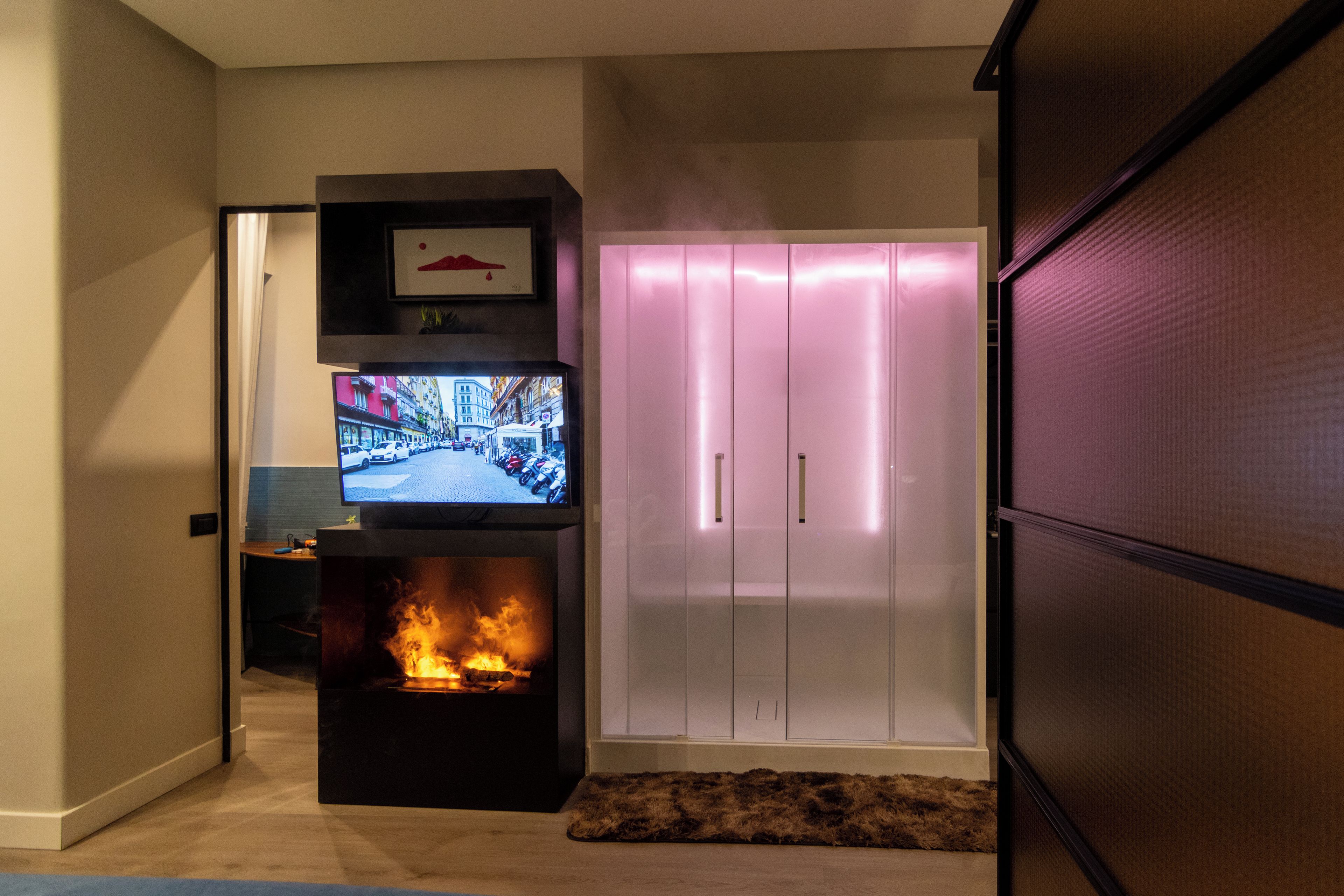 Una sala moderna con chimenea, un televisor montado sobre un soporte negro y un armario blanco con puertas correderas.