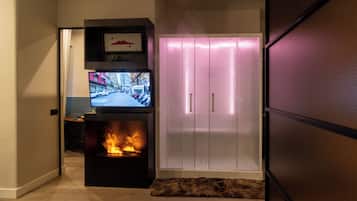 Una sala moderna con chimenea, un televisor montado sobre un soporte negro y un armario blanco con puertas correderas.