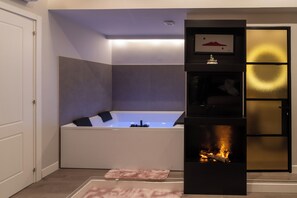 Un baño moderno con una bañera independiente, una chimenea empotrada y un cuadro enmarcado sobre la chimenea.