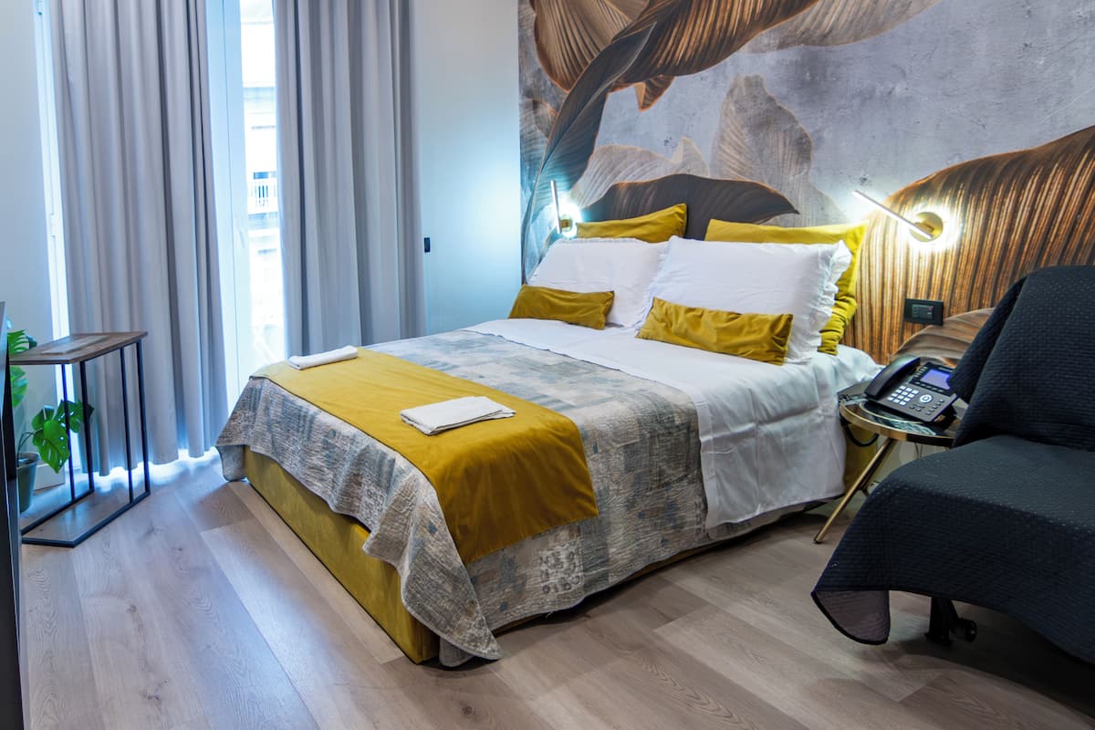 A modern hotel room with a large bed, a desk, and a chair.
