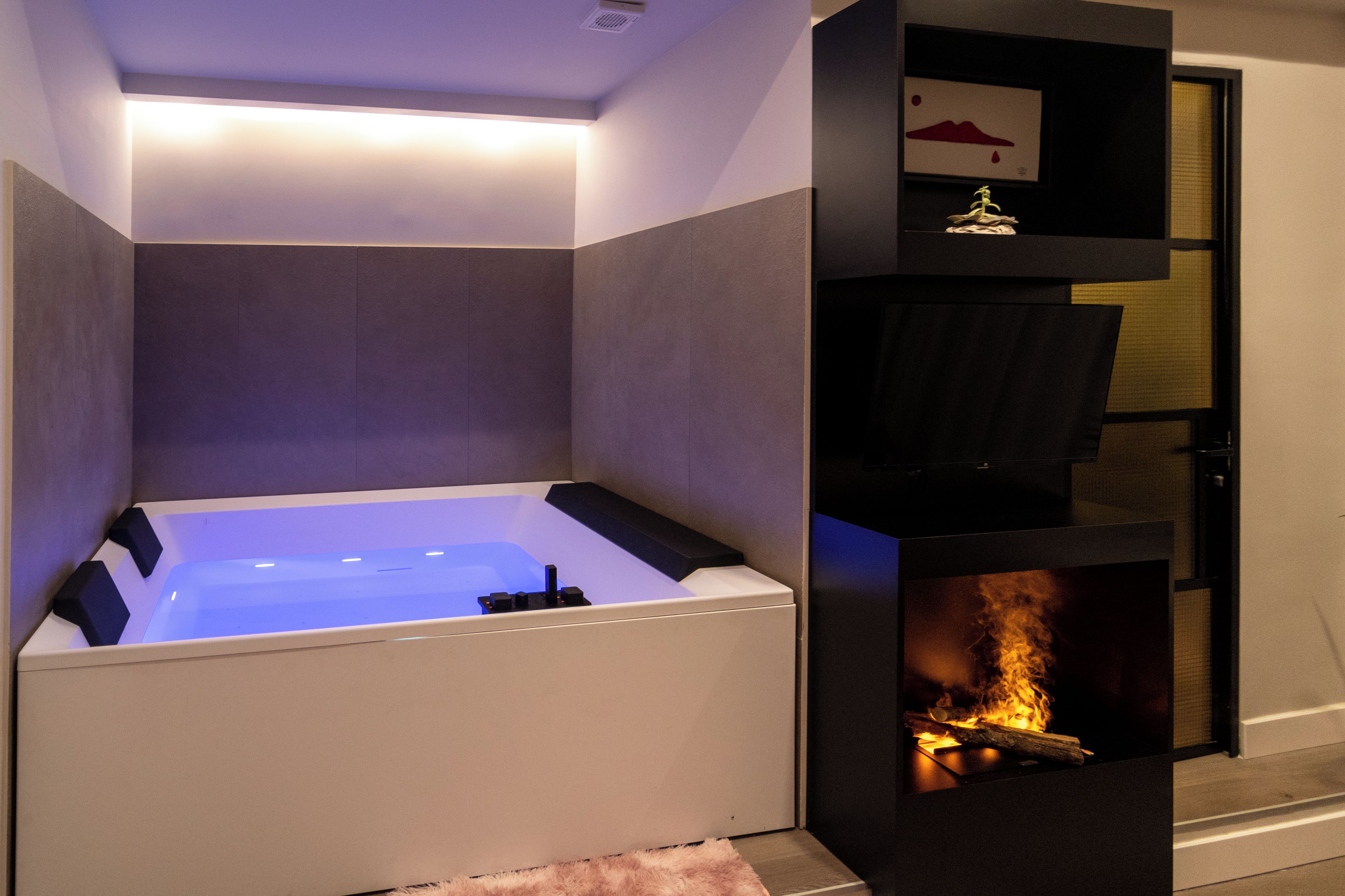 Een moderne badkamer met een ingebouwd bad, een open haard en een plank met een decoratief object.