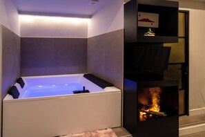 Une salle de bain moderne avec une baignoire intégrée, une cheminée et une étagère ornée d’un objet décoratif.
