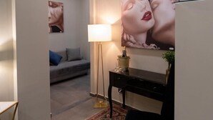 A modern living room with a grey sofa, a black side table, a floor lamp, and a large painting on the wall. - VESUVIANUS Rooms and More (Naples)