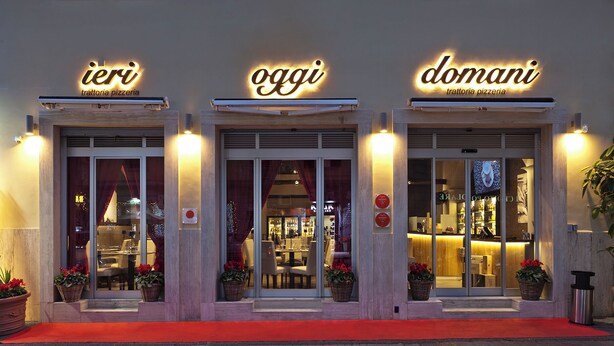A building with three illuminated signs reading "ieri," "oggi," and "domani," indicating a daily theme. - VESUVIANUS Rooms and More (Naples)
