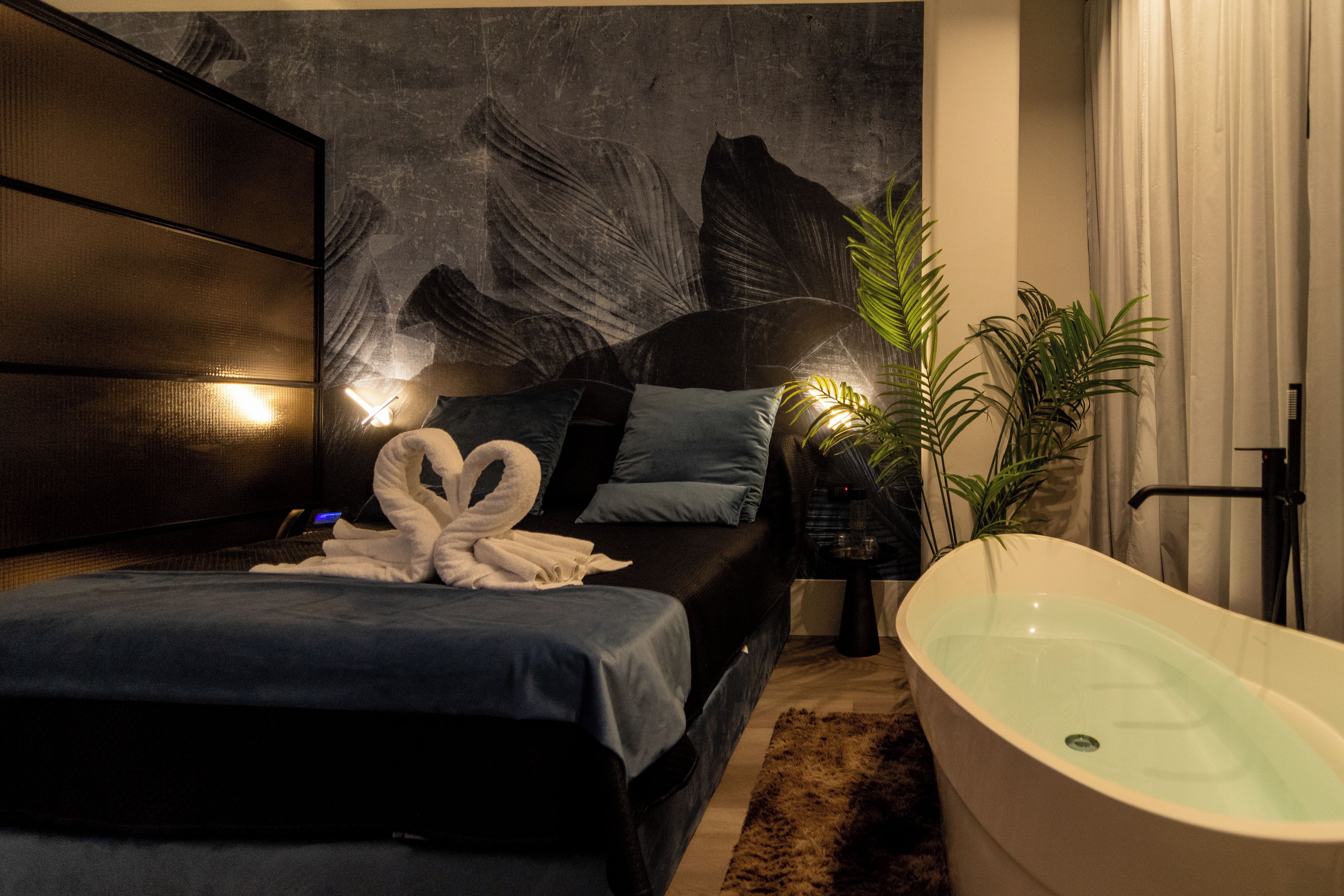 Un dormitorio moderno con una cama grande, una bañera y una pared con un diseño de hojas.