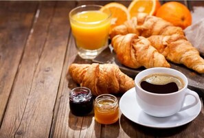 Ein Frühstückstisch mit Croissants, Orangensaft, Kaffee und Marmelade.