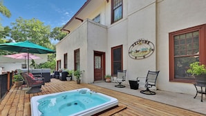 A wooden deck with a hot tub, outdoor furniture, and a welcome sign on a building. - The Lancaster Manor B&B (Gainesville)
