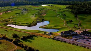 A golf course with a pond, a clubhouse, and a parking area. - The Lancaster Manor B&B (Gainesville)