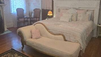 A bedroom with a bed, a chair, a lamp, and a ceiling fan.