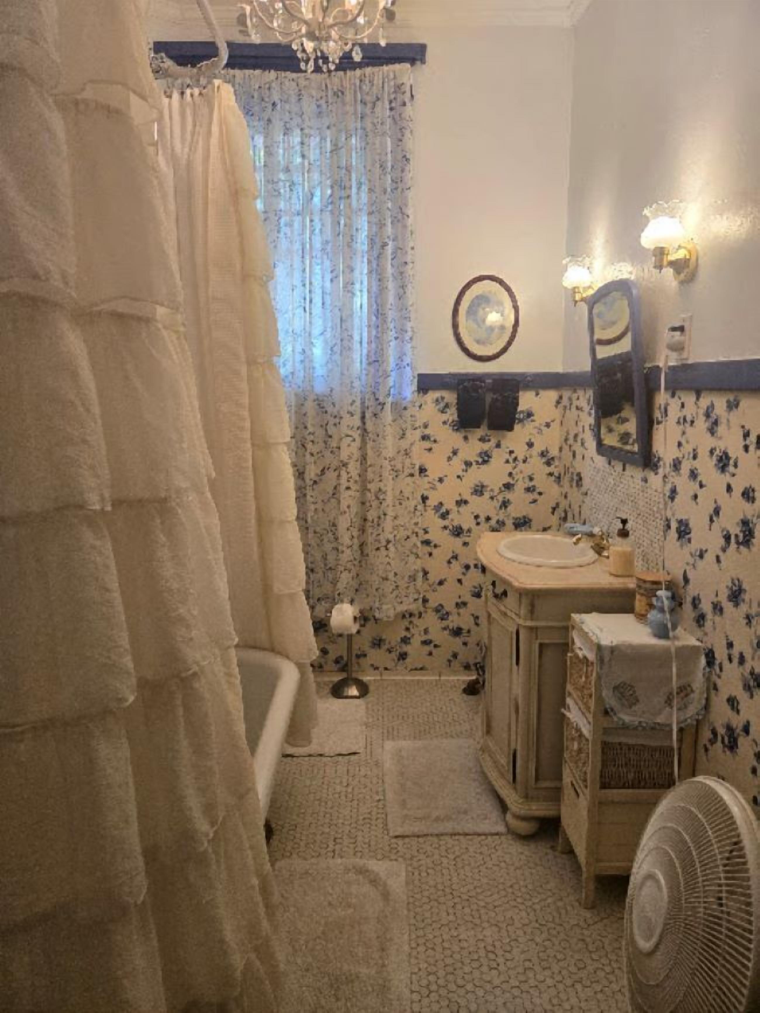 A bathroom with a bathtub, a sink, a mirror, and a fan.