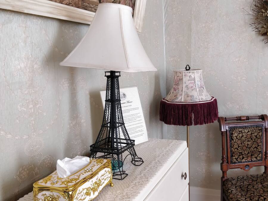 A room with a decorative lamp, a small table with a device, and a chair with a floral cushion.