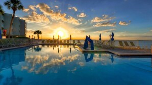 A swimming pool with a sunset view, lounge chairs, and palm trees. - Direct water view from Balcony-Pool (Tampa)